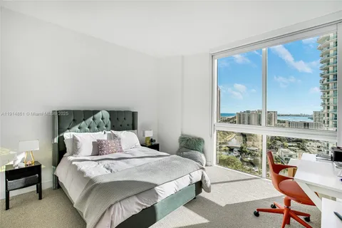 a bedroom with a bed a chair and a large window
