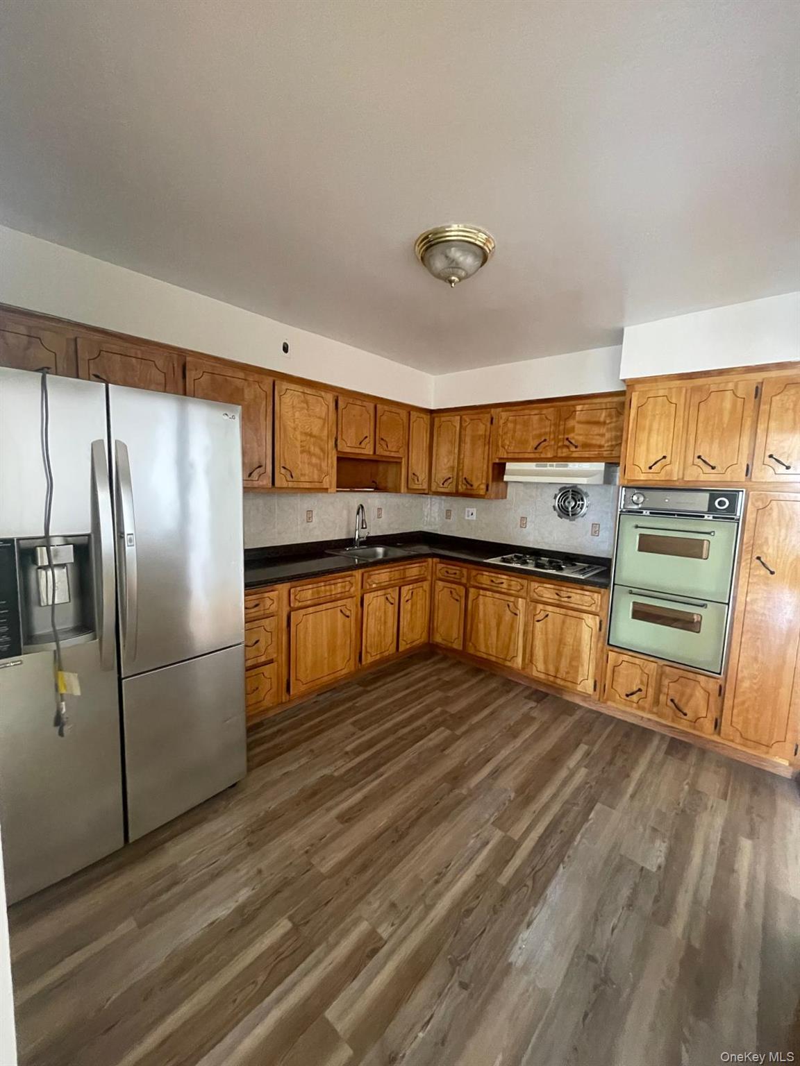 110-21 55th Avenue Queens, NY 11368 - Photo 15 of 29 a kitchen with stainless steel appliances granite countertop a refrigerator a stove and a sink with wooden floors