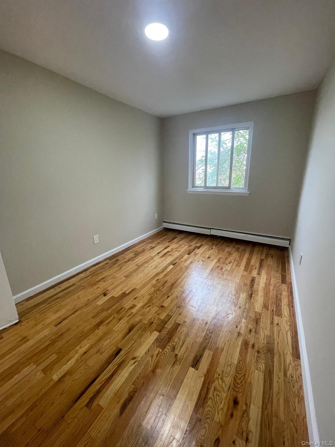 110-21 55th Avenue Queens, NY 11368 - Photo 27 of 29 wooden floor in an empty room with a window