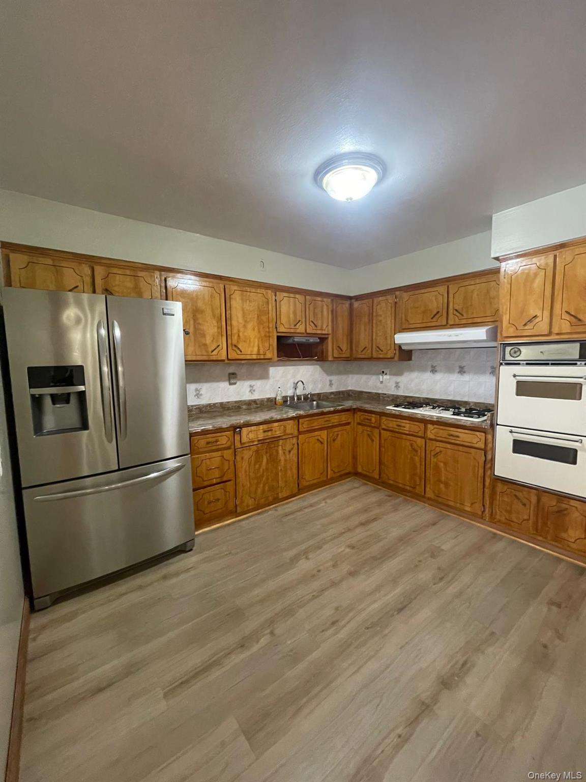 110-21 55th Avenue Queens, NY 11368 - Photo 7 of 29 a kitchen with stainless steel appliances granite countertop a refrigerator a sink dishwasher a stove with wooden cabinets and floor