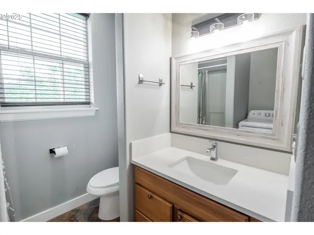 a bathroom with a sink vanity granite toilet and a mirror