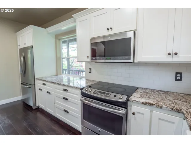 a kitchen with granite countertop a stove microwave and refrigerator
