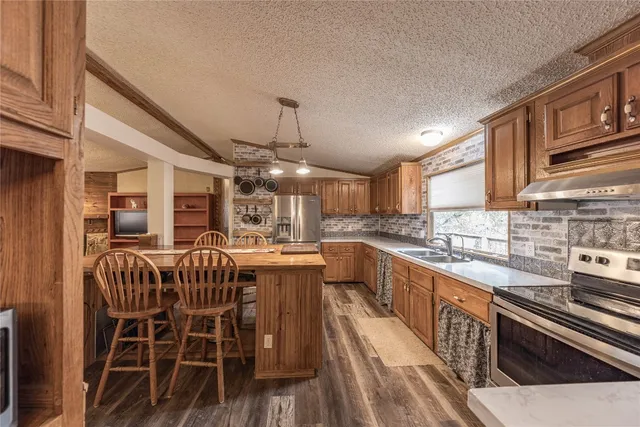 a kitchen with stainless steel appliances kitchen island granite countertop a table chairs and a refrigerator