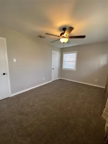 an empty room with a window and a ceiling fan