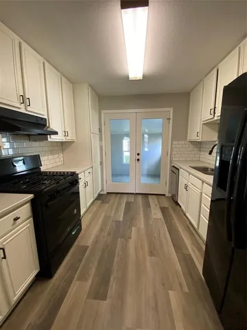 a kitchen with granite countertop a stove top oven a sink dishwasher and a refrigerator with wooden floor