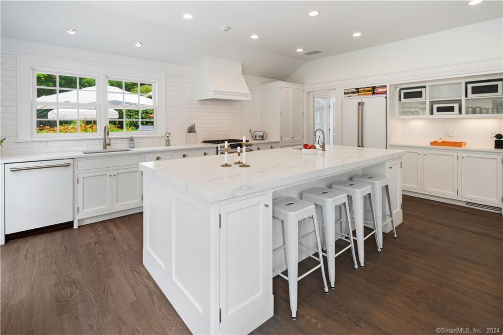 782 Smith Ridge Road New Canaan, CT 06840 - Photo 12 of 28 a large white dining hall with stainless steel appliances granite countertop a stove a sink a dining table and chairs with wooden floor