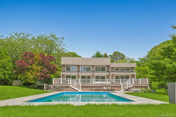 a view of a house with a big yard and potted plants and large trees
