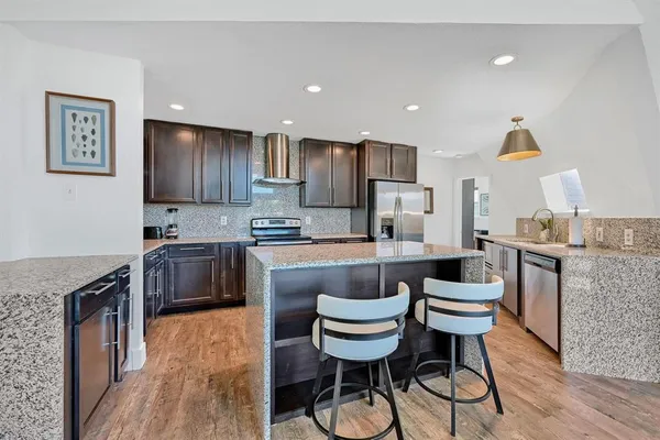 a kitchen with stainless steel appliances kitchen island granite countertop a sink cabinets and wooden floor