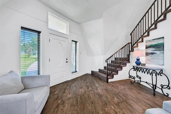 a view of an empty room with wooden floor and a rug