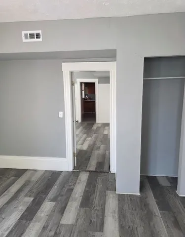 a view of a hallway with wooden floor and closet