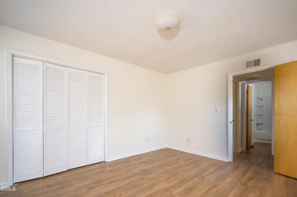 a view of an empty room with wooden floor and closet