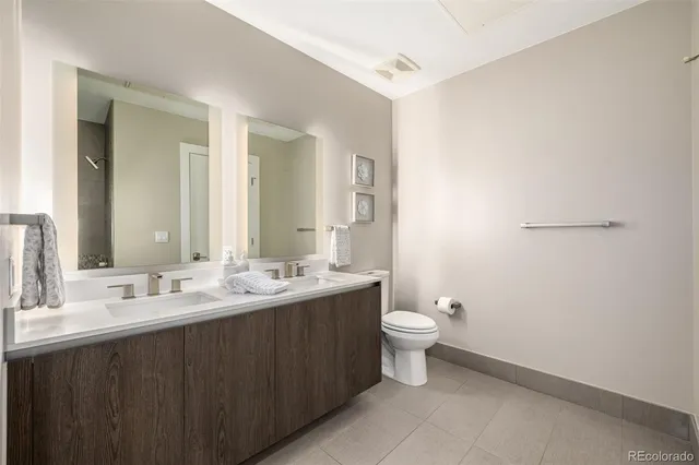 a bathroom with a double vanity sink toilet and mirror