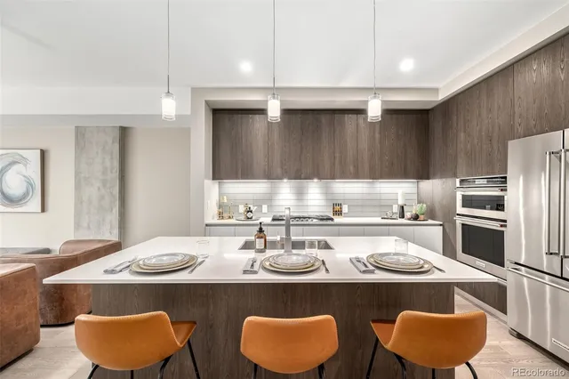 a kitchen with stainless steel appliances granite countertop a sink a stove a refrigerator and white cabinets