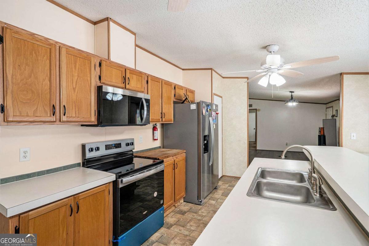 359 Norton Bridge Road Chatsworth, GA 30705 - Photo 19 of 28 a kitchen with stainless steel appliances a stove microwave and a refrigerator