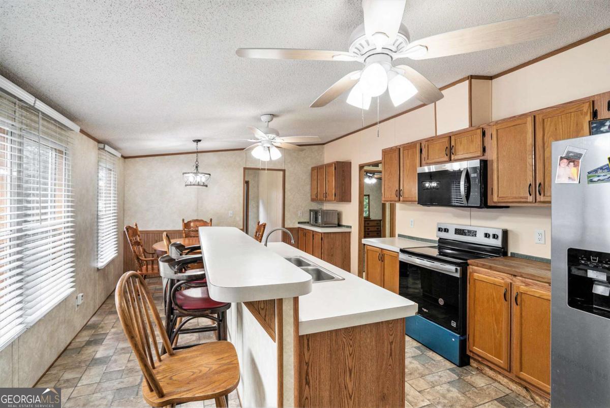 359 Norton Bridge Road Chatsworth, GA 30705 - Photo 25 of 28 a kitchen with stainless steel appliances kitchen island granite countertop a stove top oven a sink a dining table and chairs with wooden floor