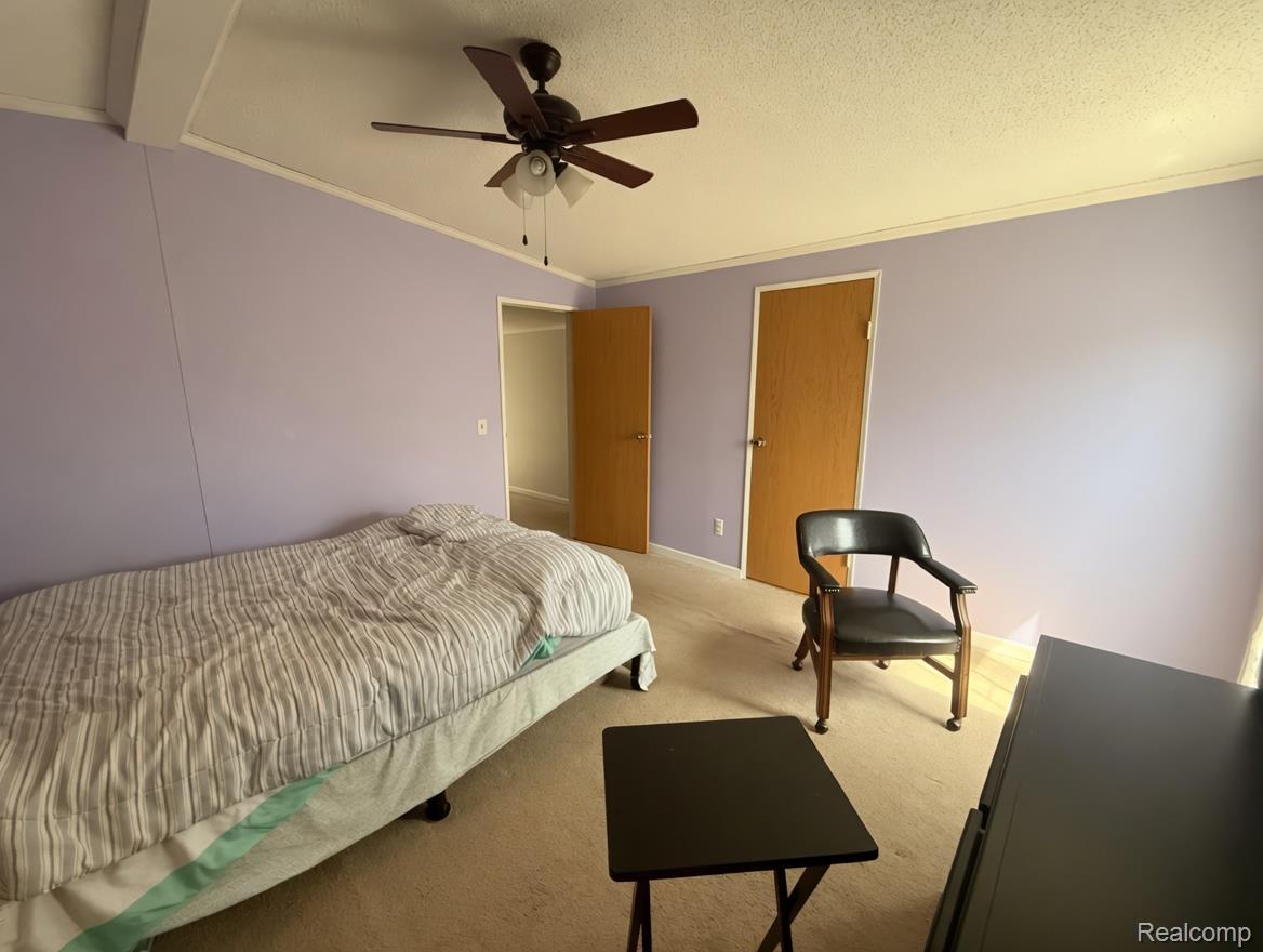 6988 McKean Road Ypsilanti, MI 48197 - Photo 13 of 21 Carpeted bedroom with ornamental molding, a textured ceiling, and ceiling fan