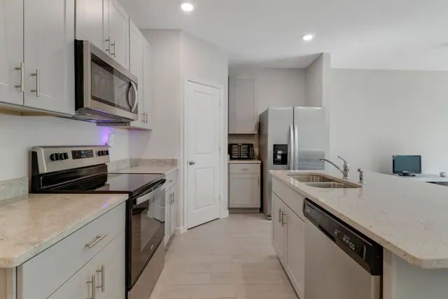 a kitchen with stainless steel appliances granite countertop a sink stove microwave and refrigerator