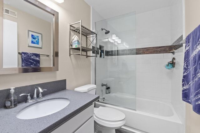 a bathroom with a granite countertop sink mirror toilet and bathtub