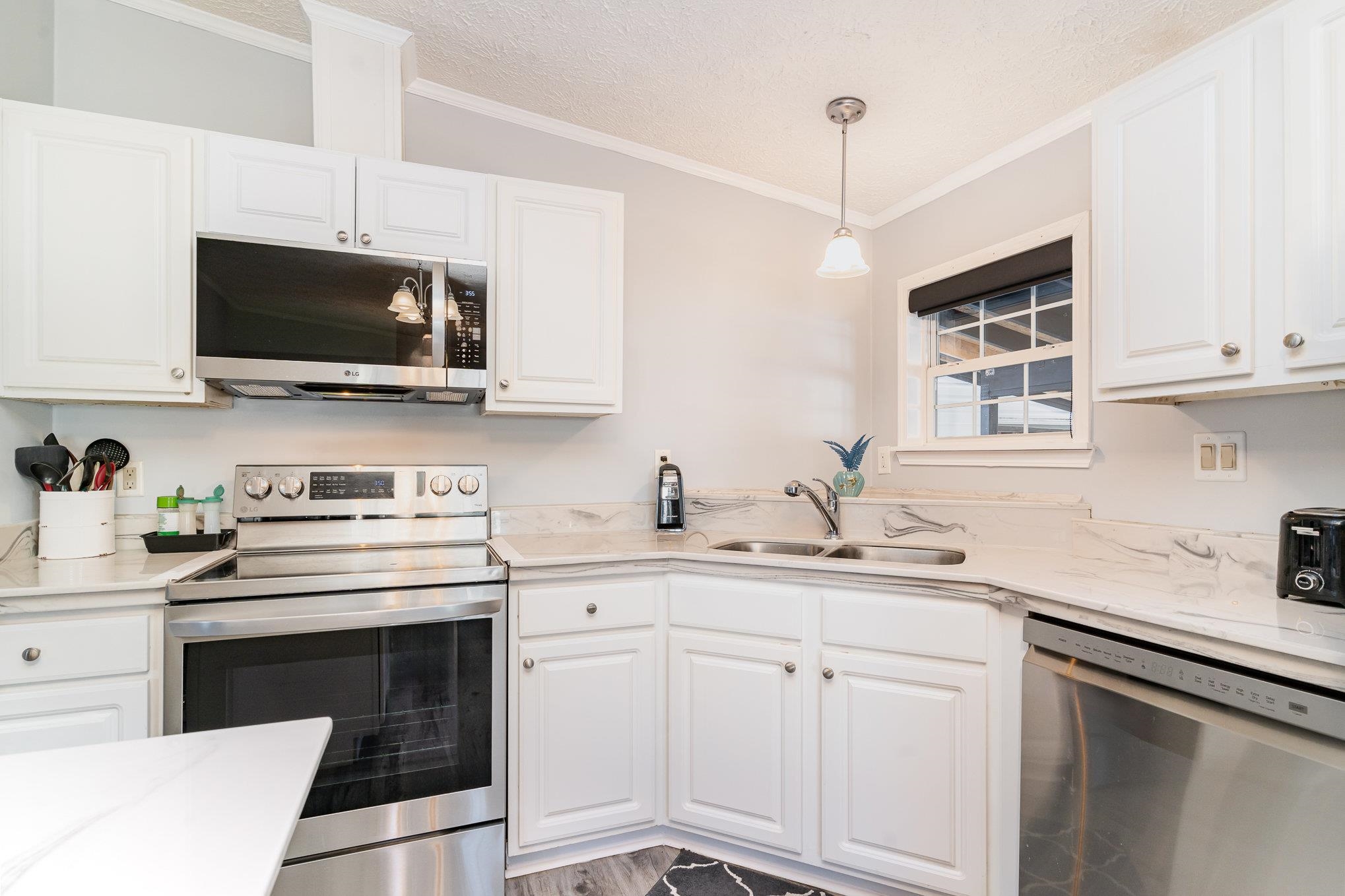 706 Oliver Drive Murrells Inlet, SC 29576 - Photo 10 of 29 Kitchen featuring crown molding, stainless steel appliances, decorative light fixtures, white cabinets, and a textured ceiling