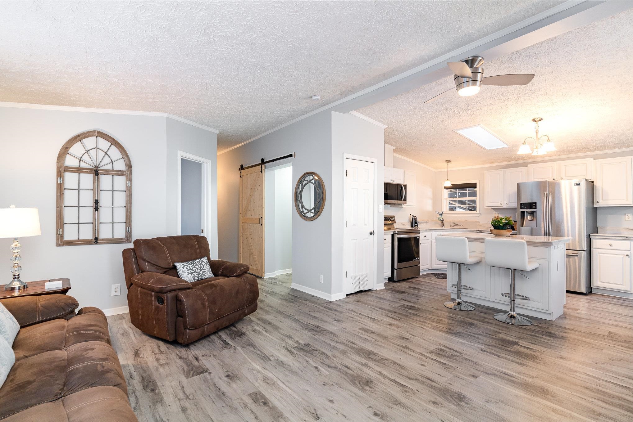 706 Oliver Drive Murrells Inlet, SC 29576 - Photo 6 of 29 Living area featuring a barn door, a textured ceiling, ceiling fan, light wood-style floors, and ornamental molding