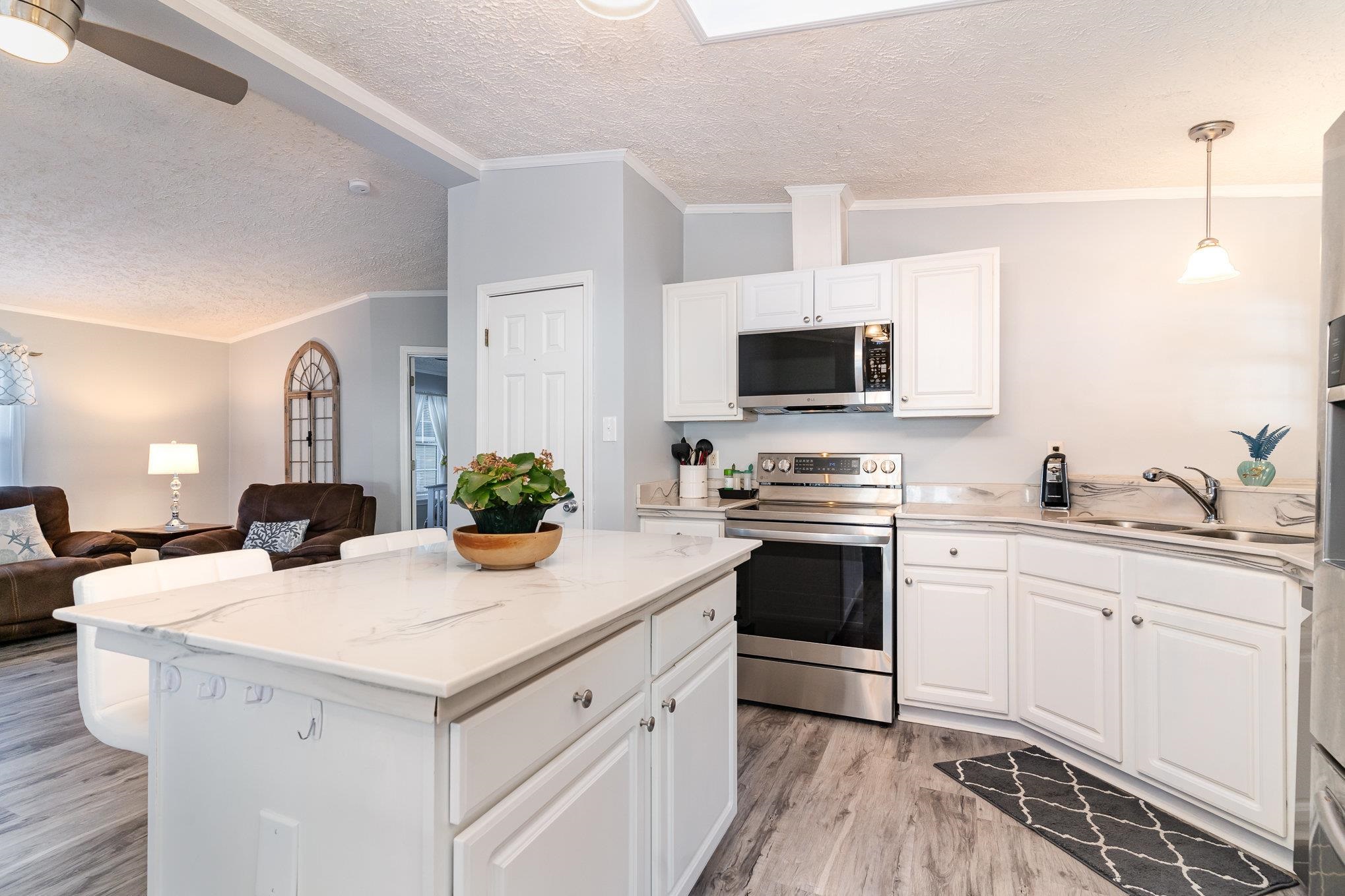 706 Oliver Drive Murrells Inlet, SC 29576 - Photo 29 of 29 Kitchen featuring crown molding, open floor plan, appliances with stainless steel finishes, a textured ceiling, and a kitchen island