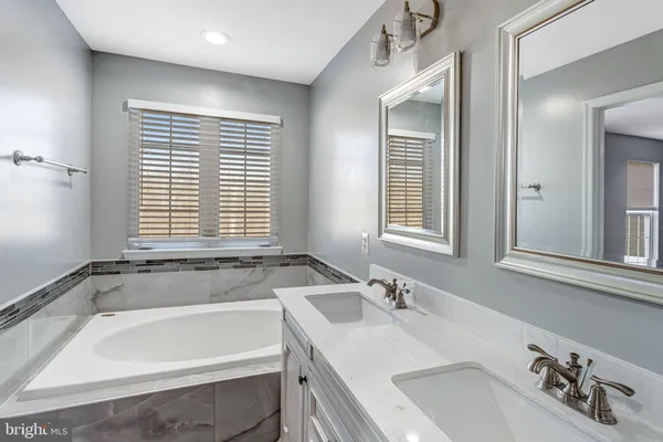 a bathroom with a tub sink and mirror