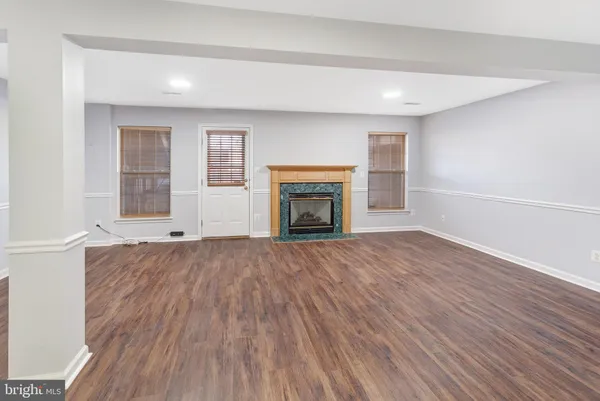 an empty room with wooden floor fireplace and windows