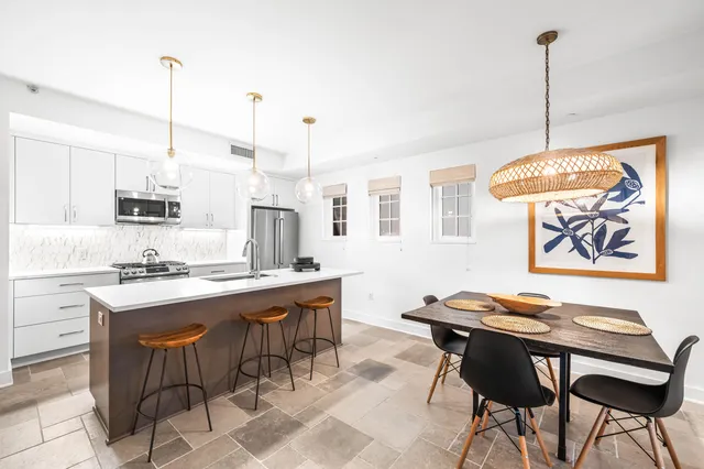a kitchen with kitchen island a sink white cabinets and stainless steel appliances