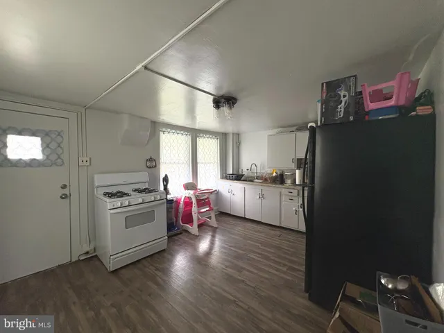 a kitchen with stainless steel appliances granite countertop a refrigerator a sink dishwasher a stove and white countertops with wooden floor