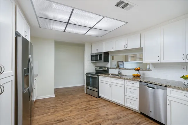 a kitchen with stainless steel appliances granite countertop a stove sink and cabinets