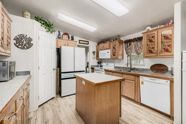 a kitchen with stainless steel appliances granite countertop a refrigerator a sink a stove and a wooden floors