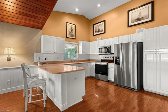 a kitchen with stainless steel appliances granite countertop a refrigerator a stove a sink dishwasher and white cabinets with wooden floor