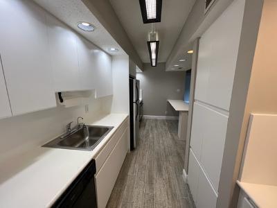 545 Trace Circle, Unit 204 Deerfield Beach, FL 33441 - Photo 4 of 10 a hallway with a white stove top oven a refrigerator and wooden floor