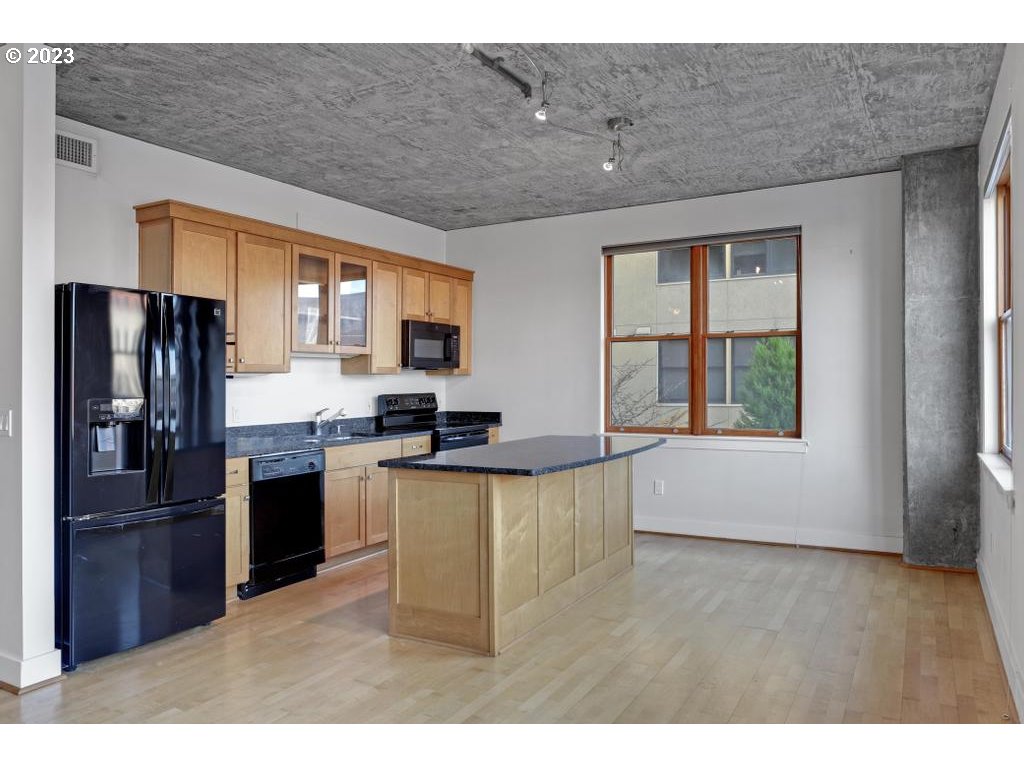 411 Northwest Flanders Street, Unit 401 Portland, OR 97209 - Photo 22 of 38 a kitchen with stainless steel appliances granite countertop a refrigerator a sink dishwasher a stove and a dining table with wooden floor