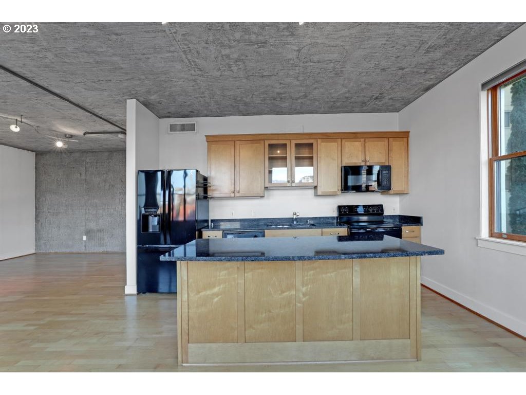 411 Northwest Flanders Street, Unit 401 Portland, OR 97209 - Photo 29 of 38 a kitchen with kitchen island granite countertop a sink cabinets and window