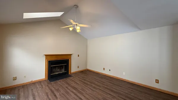 a view of an empty room with wooden floor and a fireplace