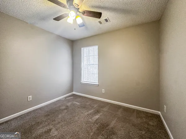 an empty room with a window and a chandelier fan