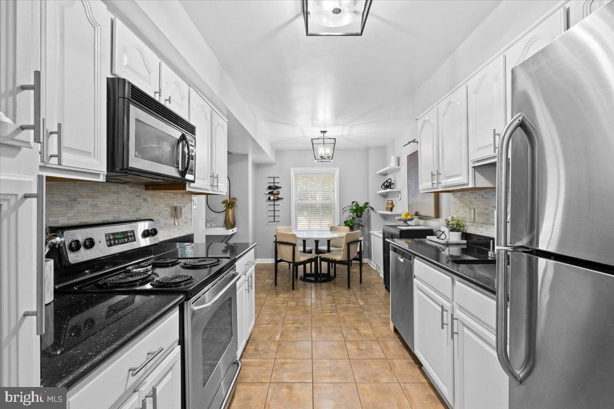 3332 Spring Lane, Unit C10 Falls Church, VA 22041 - Photo 6 of 25 a kitchen with stainless steel appliances granite countertop a stove top oven a sink a refrigerator white cabinets and wooden floor