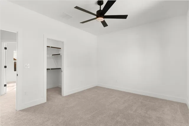 an empty room with white walls and ceiling fan