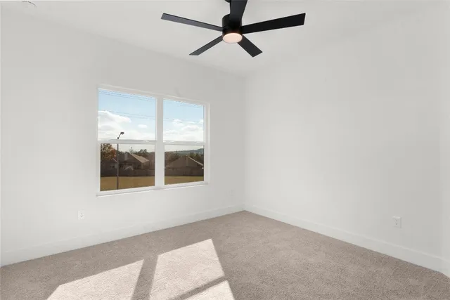 an empty room with a window and a ceiling fan