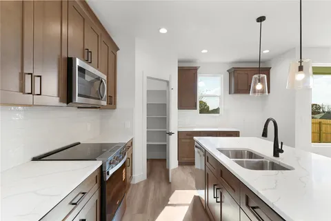 a kitchen with stainless steel appliances granite countertop a sink a stove and a wooden floors