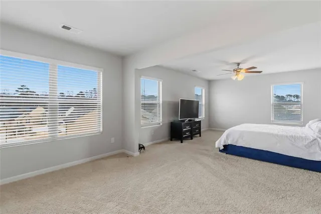 a spacious bedroom with a bed a couch and a flat screen tv