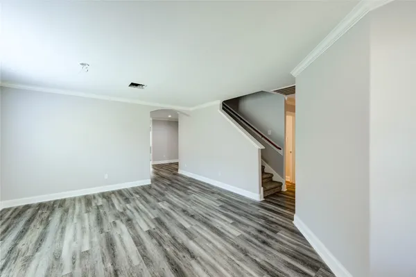 a view of an empty room with wooden floor and stairs