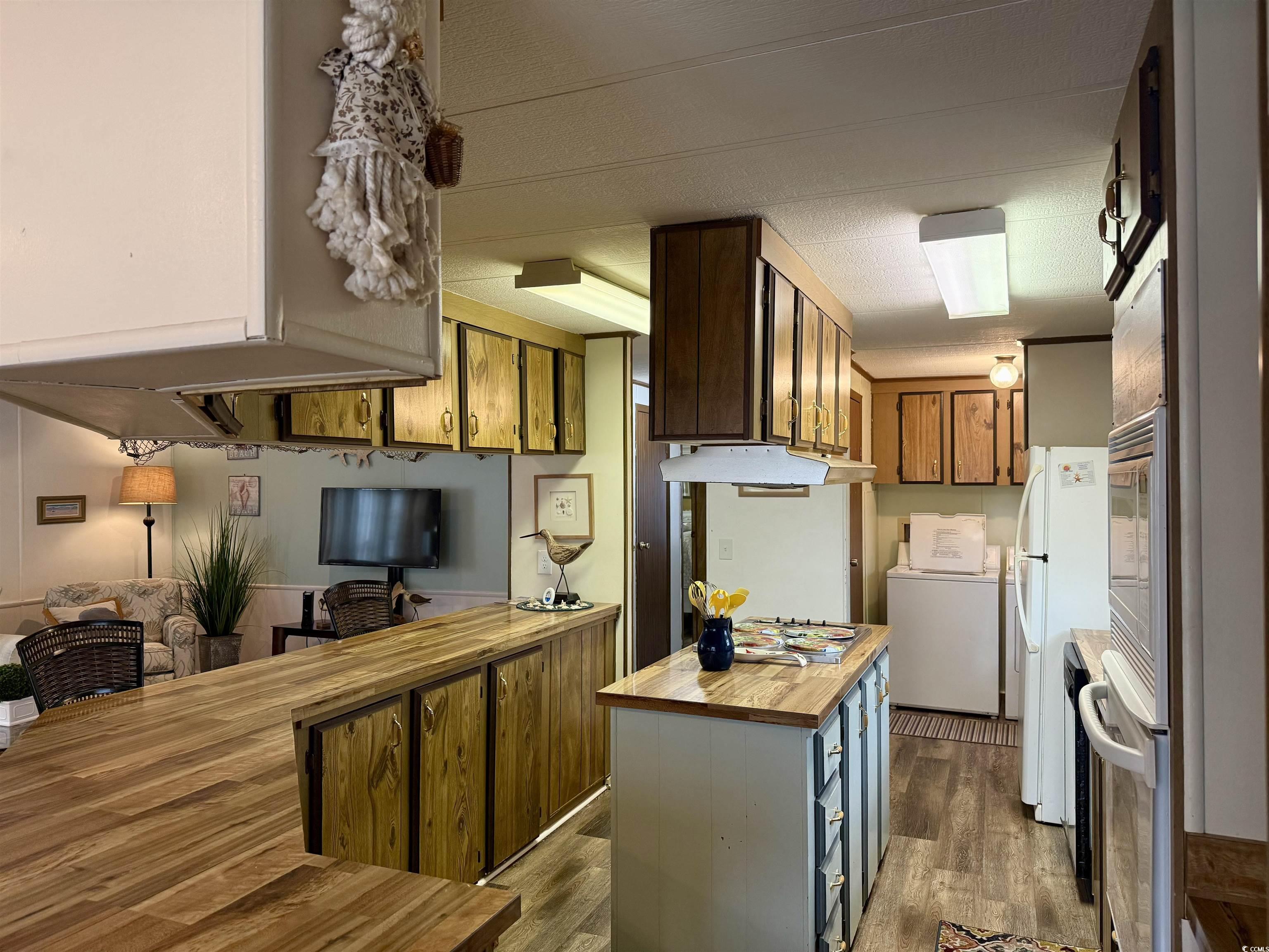 1801 E Lake Surfside Beach, SC 29575 - Photo 5 of 32 Kitchen featuring butcher block countertops, a peninsula, dark wood finished floors, and washer / dryer