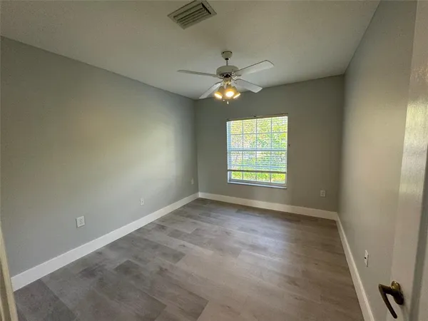 an empty room with windows and fan
