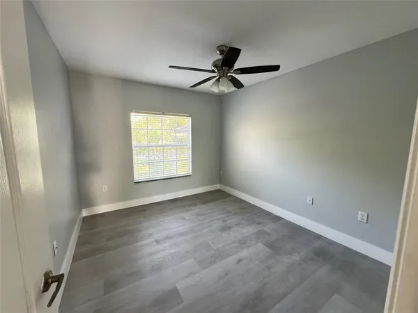 an empty room with windows and fan