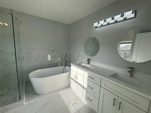 a bathroom with a double vanity sink a mirror and bathtub