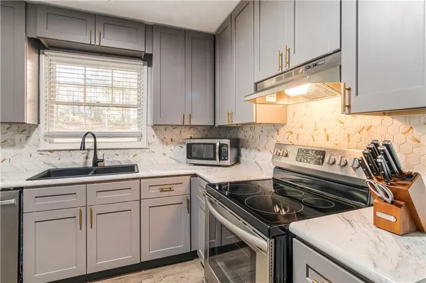 a kitchen with white cabinets appliances and a sink