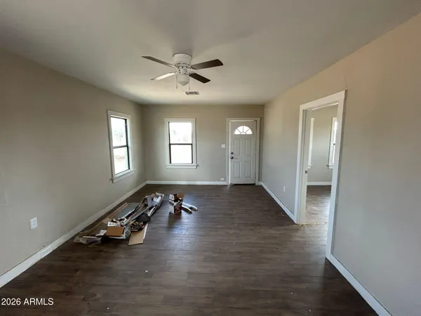 a view of an empty room with wooden floor and a window