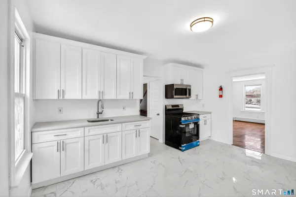 a kitchen with white cabinets and black appliances